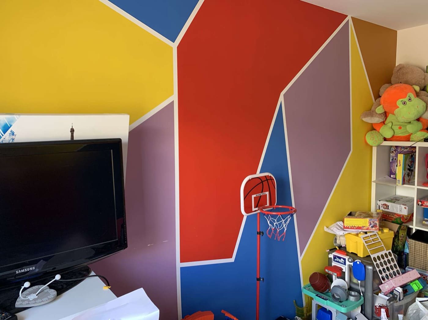Chambre d'enfant peinte en formes géométriques rouge, jaune, bleu et prune
